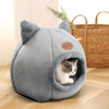 Chaton curieux dans une Niche Chat Intérieur Igloo Chat grise à côté d’un panier en osier.