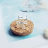 Bague chat argentée posée sur un support naturel.