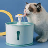 Chat blanc buvant à une fontaine pour chat design fleur dans un décor pastel.