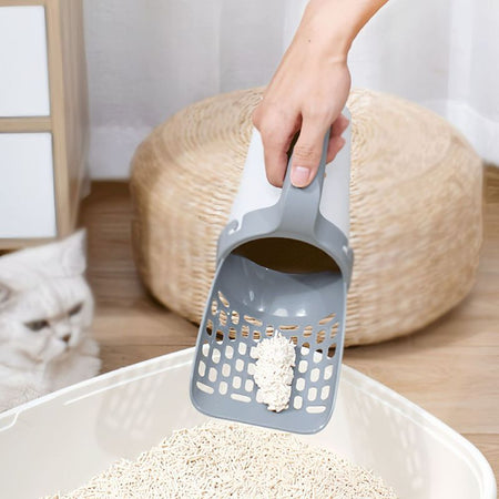 Utilisation d’une Pelle à Litière pour Chat dans un bac rempli de litière végétale.