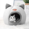 Chat qui observe depuis l'entrée de la Niche Chat Intérieur Igloo Chat sur tapis blanc.