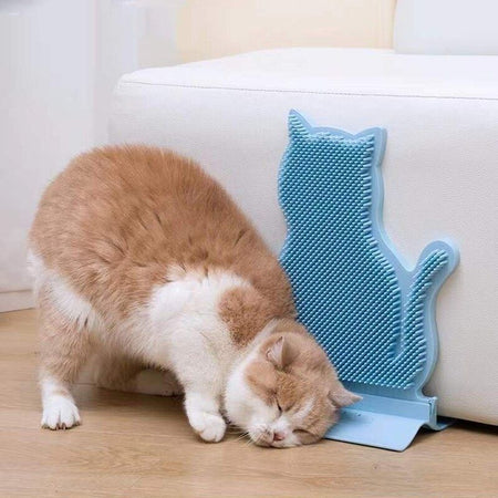 Chat roux profitant d’un moment de massage avec une brosse murale bleue.